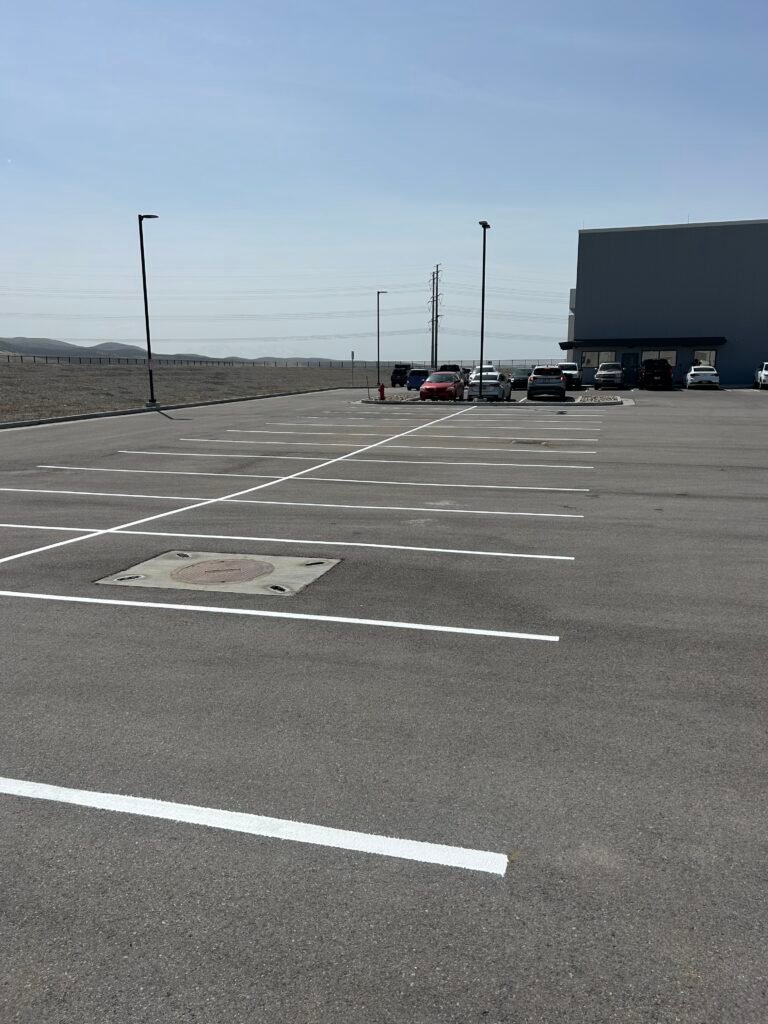 Freshly painted white parking stall lines across large commercial asphalt lot